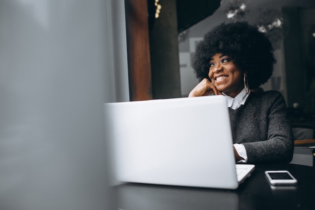 Femme afro américaine avec ordinateur portable et téléphone dans un café