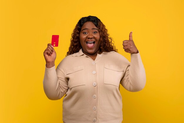 Une femme afro-américaine pauvre et heureuse montrant sa carte de crédit.