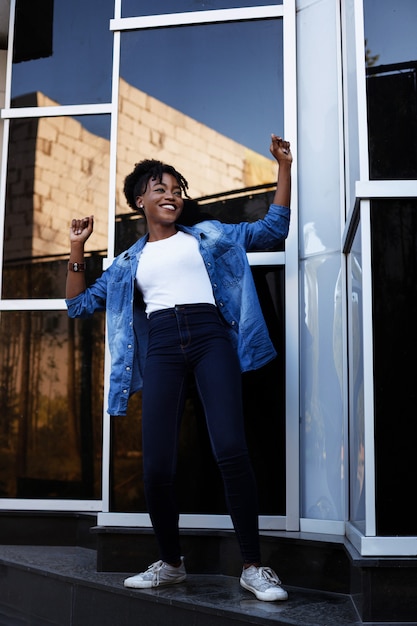 Une femme afro-américaine à la peau sombre est heureuse et danse sur une promenade dans la ville en été. Égalité