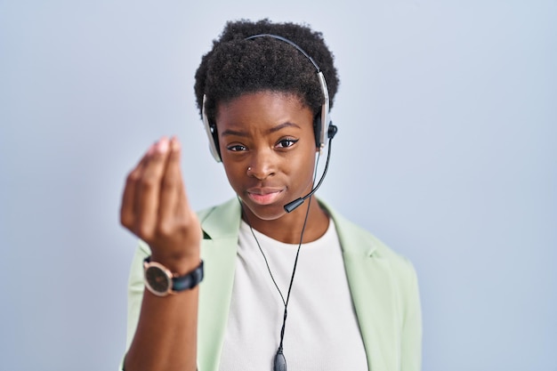 Femme afro-américaine portant un casque d'agent de centre d'appel faisant un geste italien avec la main et les doigts expression confiante
