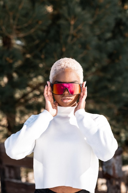 Une femme afro-américaine portant des lunettes de neige sur une montagne enneigée en hiver