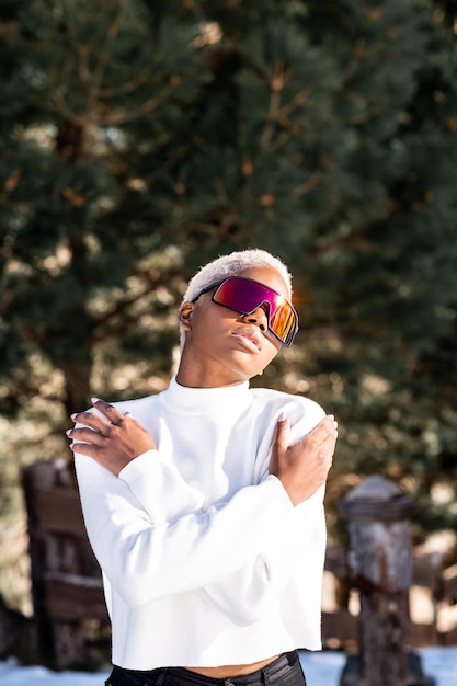 Une femme afro-américaine portant des lunettes de neige sur une montagne enneigée en hiver