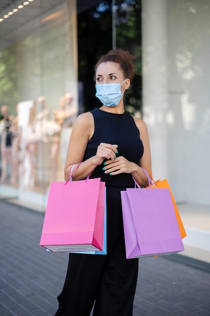 Femme afro-américaine portant un masque anti-virus avec des sacs en papier colorés