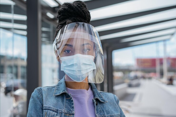 Photo femme afro-américaine portant un masque médical de protection faciale en plastique regardant la caméra
