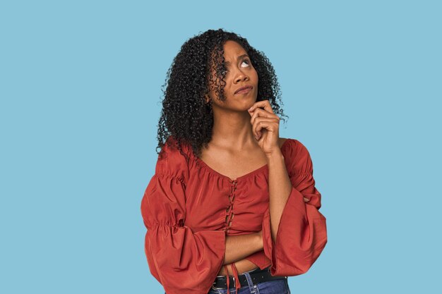 Photo une femme afro-américaine qui pense et regarde en haut, qui réfléchit, qui envisage d'avoir un fantasme.