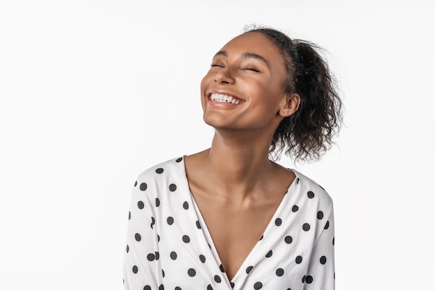 Femme afro-américaine riant et fermant les yeux avec plaisir isolé sur fond blanc