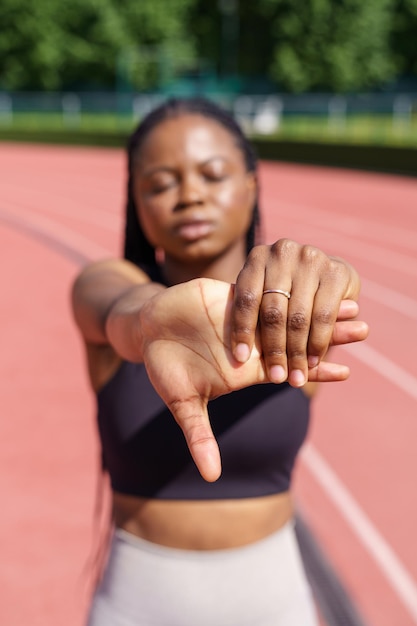 Une femme afro-américaine s'étire les mains pour se réchauffer avant un entraînement intensif le jour d'été ensoleillé