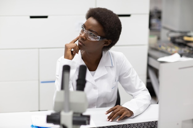 Femme afro-américaine scientifique travaillant en laboratoire avec des instruments électroniques