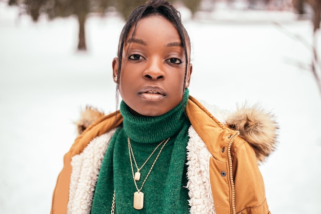 Femme afro-américaine sérieuse debout dans la rue à l'extérieur avec fond de neige blanche