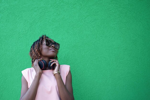 Une femme afro-américaine souriante écoute de la musique avec des écouteurs Technologies sans fil Copier l'espace