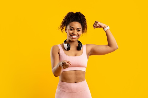 Une femme afro-américaine souriante avec les poings en forme.