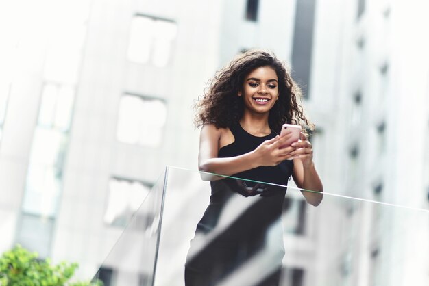 Une femme afro-américaine souriante et souriante a une bonne conversation dans la rue.