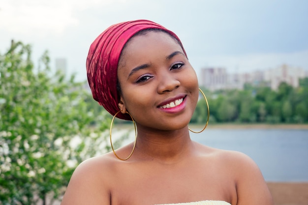 Femme afro-américaine souriante tenant le drapeau américain et regardant la caméra automne soir printemps dans le parc au bord du lac