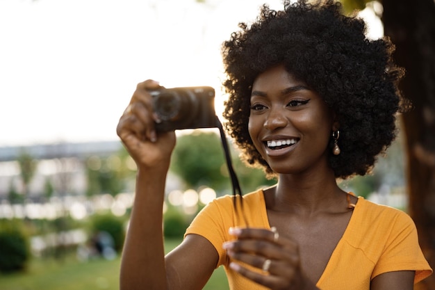 Femme afro-américaine souriante utilisant une caméra professionnelle dans une rue