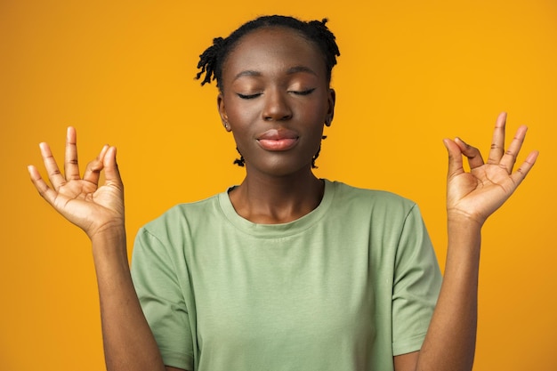 Femme afro-américaine souriante les yeux fermés faisant de la méditation