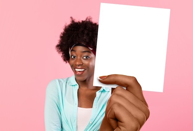 Femme afro-américaine tenant une carte vierge debout sur fond rose