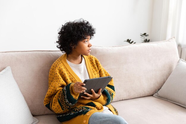 Femme afro-américaine tenant une tablette numérique à écran tactile tapant la page de défilement à la maison Femme avec un appareil de technologie mobile surfant sur Internet en utilisant des applications de médias sociaux jouant au jeu