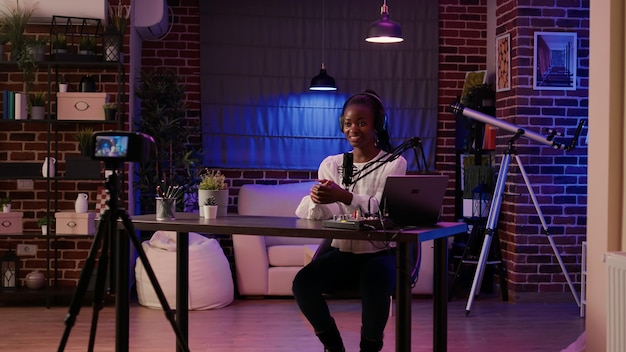Femme Afro-américaine Vlogger Saluant Le Public Tout En Enregistrant Un Vlog à L'aide D'une Caméra Vidéo Numérique Depuis Un Studio De Podcasting à Domicile. Célèbre Influenceur Créant Du Contenu En Direct Pour La Page De Médias Sociaux En Ligne.