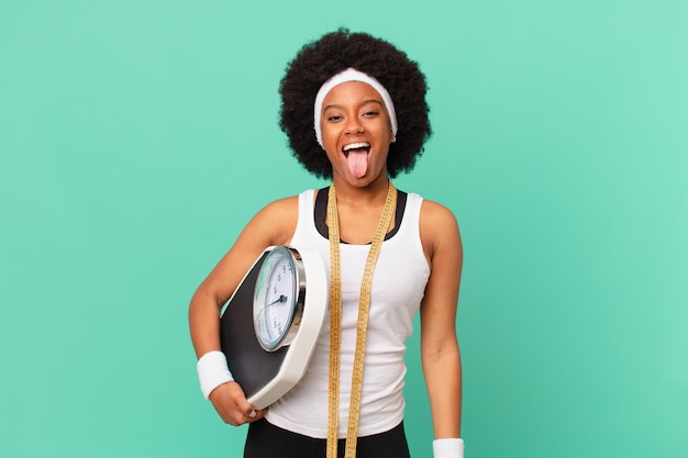 Femme afro avec une attitude gaie, insouciante, rebelle, plaisantant et tirant la langue, s'amusant concept de régime