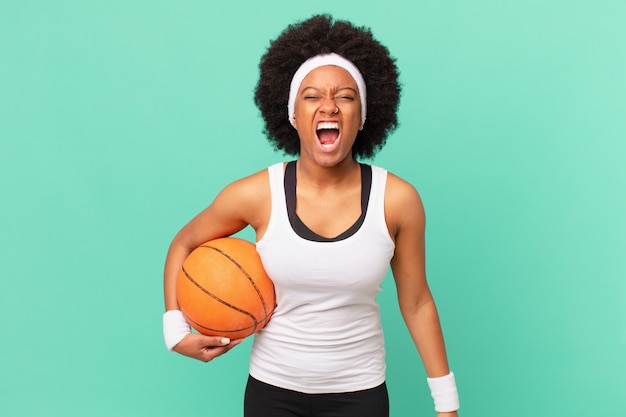 Femme afro criant agressivement, semblant très en colère, frustrée, indignée ou agacée, criant non. concept de basket-ball
