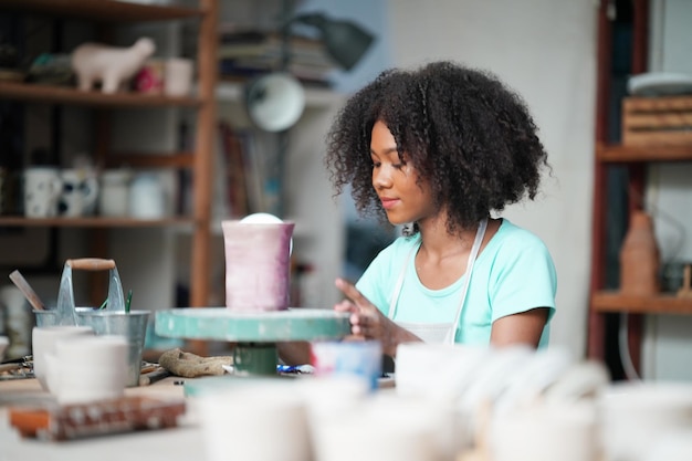 Femme afro faisant de la poterie en atelier Façonner de l'argile humide sur un tour de potier