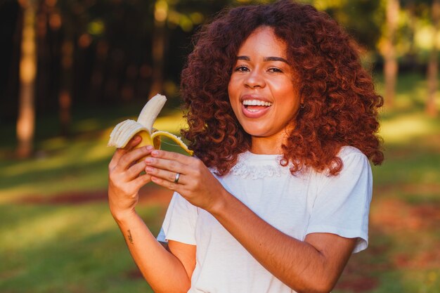 Femme afro, manger, banane, dans parc