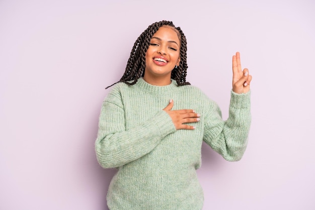 Femme afro noire à l'air heureuse, confiante et digne de confiance, souriante et montrant le signe de la victoire, avec une attitude positive