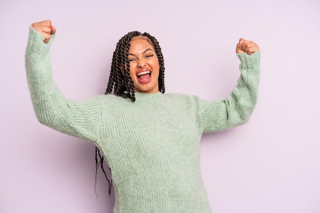 Femme afro noire criant triomphalement, ressemblant à un gagnant excité, heureux et surpris, célébrant