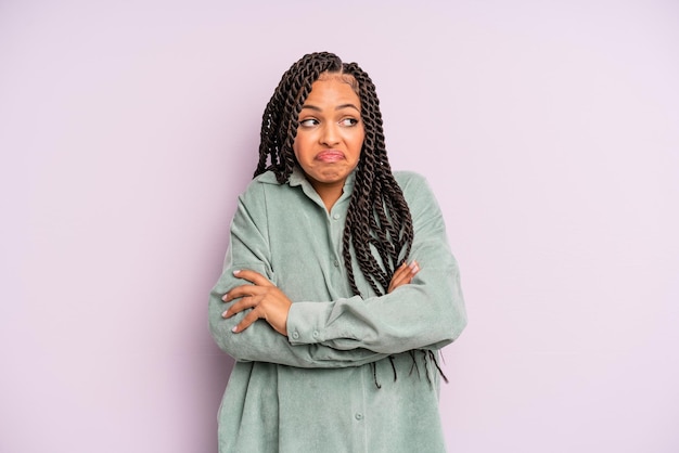 Femme afro noire haussant les épaules, se sentant confuse et incertaine, doutant avec les bras croisés et le regard perplexe