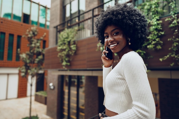 Femme afro noire parlant au téléphone portable dans la ville