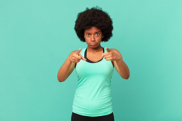 Femme afro noire portant des vêtements de fitness contre un mur isolé