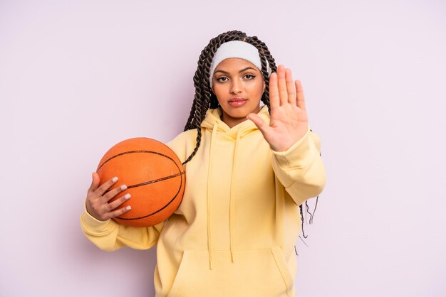 Femme afro noire à la recherche sérieuse montrant la paume ouverte faisant le concept de basket-ball de geste d'arrêt