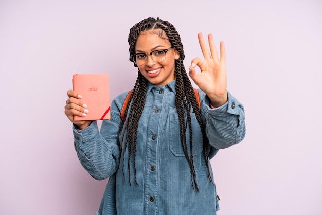 Femme afro noire se sentant heureuse, montrant son approbation avec un geste correct. calendrier étudiant ou concept d'agenda