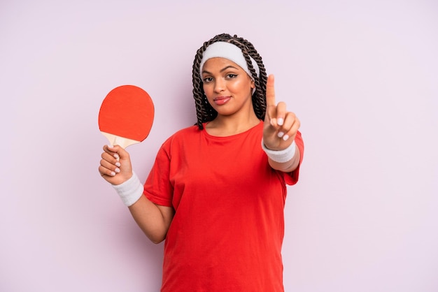 Femme afro noire souriant fièrement et en toute confiance faisant le concept de ping-pong numéro un