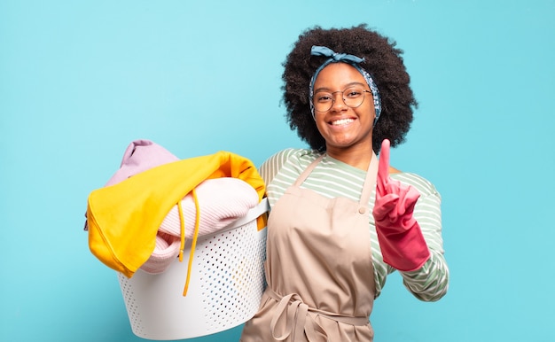 Femme afro noire souriant fièrement et en toute confiance faisant la pose numéro un triomphalement, se sentant comme un leader. concept de ménage ... concept de ménage