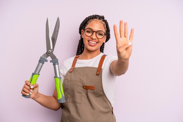 Femme afro noire souriante et amicale montrant le concept de jardinier ou d'agriculteur numéro quatre