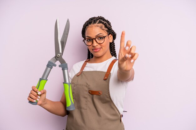 Femme afro noire souriante et sympathique, montrant le numéro un. concept de jardinier ou d'agriculteur