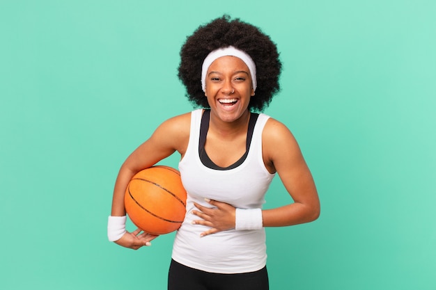 Femme afro riant à haute voix à une blague hilarante, se sentant heureuse et joyeuse, s'amusant. concept de basket-ball