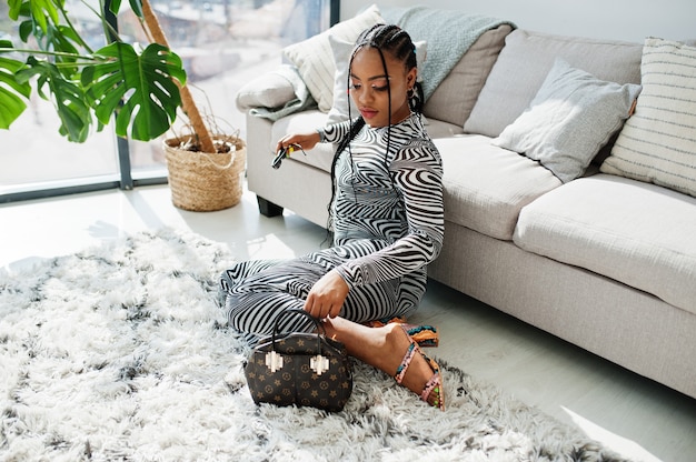 Femme afro en robe zébrée assise à l'intérieur