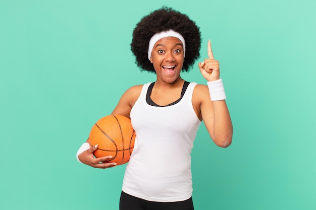 Femme afro se sentant comme un génie heureux et excité après avoir réalisé une idée levant joyeusement le concept de basket-ball eureka doigt