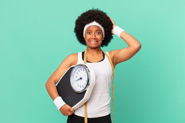 Femme afro se sentant stressée, inquiète, anxieuse ou effrayée, les mains sur la tête, paniquant devant le concept de régime d'erreur