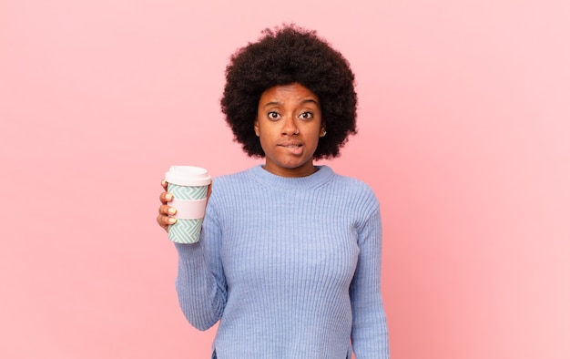 Femme afro semblant perplexe et confuse, mordant la lèvre avec un geste nerveux, ne connaissant pas la réponse au problème. concept de café