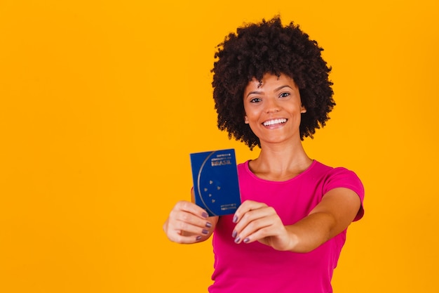 Femme afro souriante tenant un passeport brésilien dans les mains