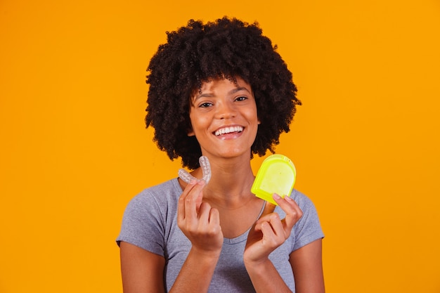 Femme afro tenant une plaque de blanchiment. Appareil invisible.