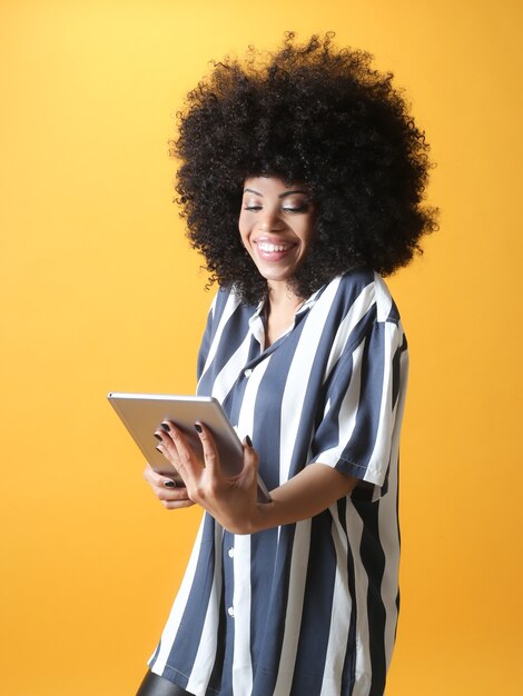 Femme afro, utilisant une tablette sur fond jaune