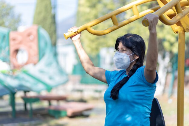 Femme d'âge mexicaine s'entraînant sur une aire de jeux portant un masque facial en raison d'une pandémie