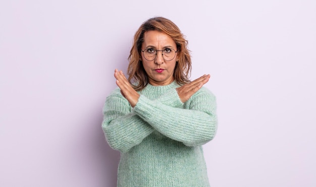 Femme d'âge moyen ayant l'air ennuyée et malade de votre attitude, en disant assez ! les mains croisées devant, vous disant d'arrêter