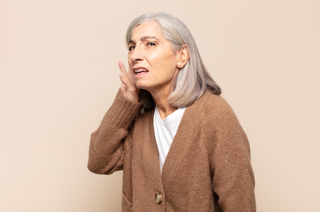 Femme d'âge moyen ayant l'air sérieuse et curieuse, écoutant, essayant d'entendre une conversation secrète ou des potins, écoutant aux portes