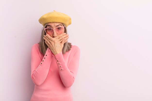 Femme d'âge moyen couvrant la bouche avec les mains avec un choqué