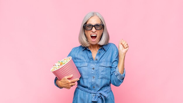 Femme d'âge moyen criant agressivement avec une expression de colère ou avec les poings serrés célébrant le concept de film de succès